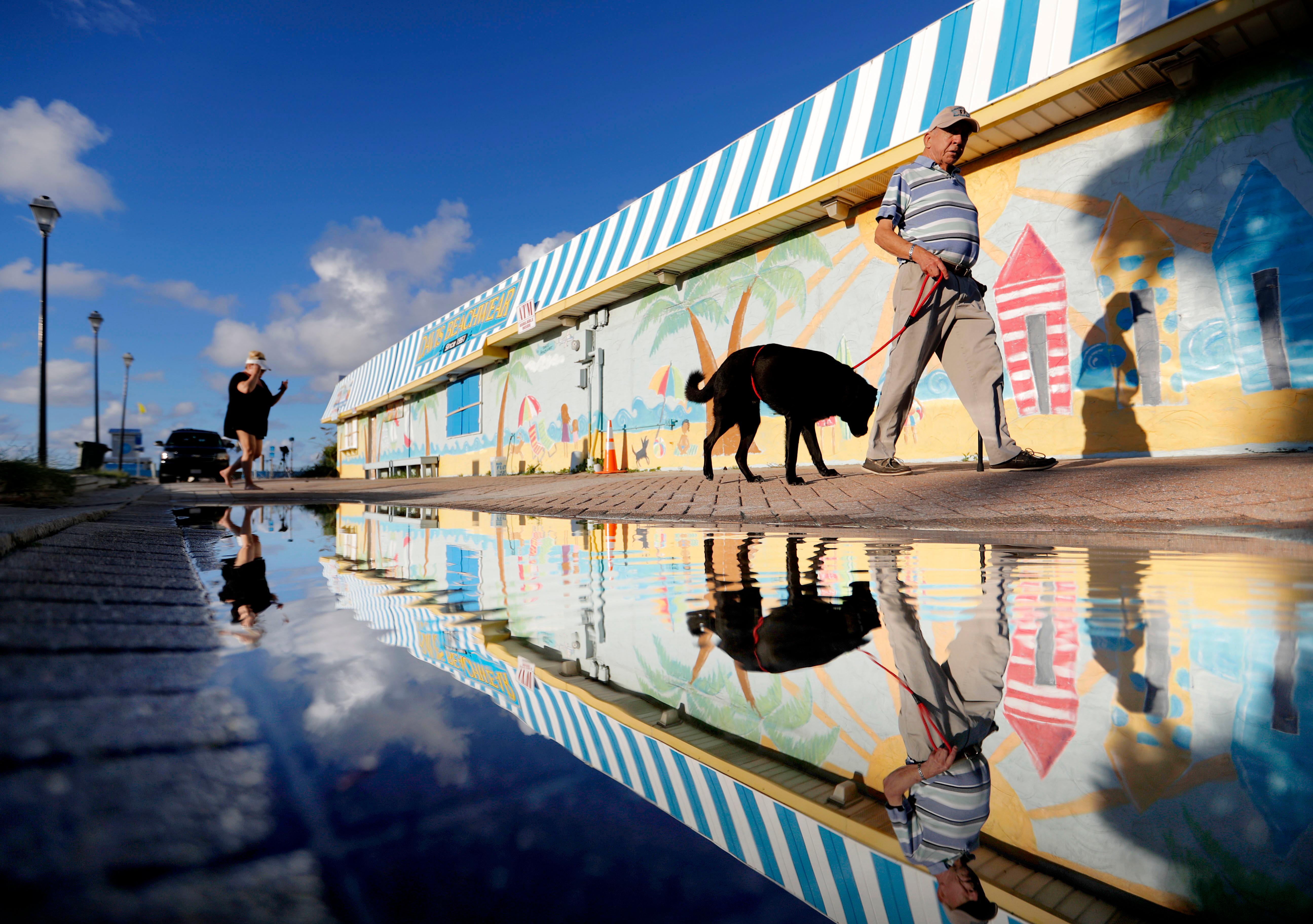 beachgoers walk past a mural along the boardwalk as hurricane